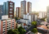 Novos modelos de moradia no Brasil: Microapartamentos, coliving e “imóvel por assinatura” ganham força Fachadas de prédios pequenos com jovens entrando e saindo — representando moradia alternativa urbana.